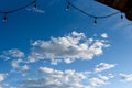 Rustic background of outdoor wood ceiling and string of lights framing a blue sky with white clouds Royalty Free Stock Photo