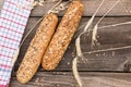 Rustic baguette and wheat on an old planked wood table.