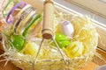 A rustic basket with Easter eggs on a wooden windowsill bathed in sunlight. Above view. Easter decor Royalty Free Stock Photo