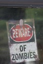 rustic beware of zombies sign found posted on dusty window Royalty Free Stock Photo