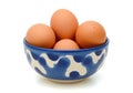 A rustic blue ceramic bowl filled with fresh brown chicken eggs on a white background Royalty Free Stock Photo