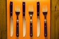 Rustic blue silverware on orange setting with wooden background Royalty Free Stock Photo