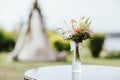 Rustic bouquet of different flowers in a vase on the wigwam background, preparing for event Royalty Free Stock Photo