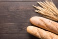 Rustic bread or baguette and wheat ears on the wooden background Royalty Free Stock Photo