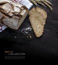 Rustic bread loaf and slices on dark wood fading to black, sampl