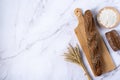 Rustic bread roll or french baguette, wheat and flour on a light background.