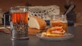 Rustic breakfast with a piece of bread and jam, a glass of hot tea in an antique silver cup holder and a jar of jam on a gray Royalty Free Stock Photo