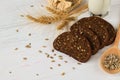 Rustic breakfast on a white wooden background - bread, sunflower, seeds on a light spoon, ears of wheat and a glass of milk