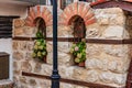 Rustic brick and stone wall with arched windows and floral decor Royalty Free Stock Photo