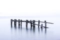 Rustic broken pier wooden posts standing in calm blue lake water Royalty Free Stock Photo