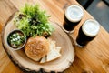 Rustic burger and beer setup with fresh greenery on wooden table Royalty Free Stock Photo