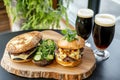Rustic burger and beer setup with fresh greenery on wooden table Royalty Free Stock Photo
