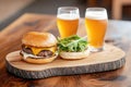Rustic burger and beer setup with fresh greenery on wooden table Royalty Free Stock Photo