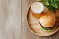Rustic burger and beer setup with fresh greenery on wooden table Royalty Free Stock Photo