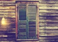 Rustic cabin window with closed shutters and porch light