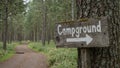 Rustic Campground sign on tree in mossy forest arrow pointing down winding path Royalty Free Stock Photo