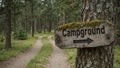 Rustic Campground sign on tree in mossy forest arrow pointing down winding path Royalty Free Stock Photo