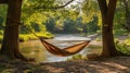 A rustic campsite by a river with a hammock tied between two trees Royalty Free Stock Photo