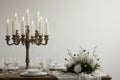 A rustic candlelit dinner setting featuring an antique wooden table set against a stark white background