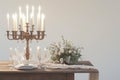 A rustic candlelit dinner setting featuring an antique wooden table set against a stark white background