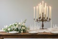 A rustic candlelit dinner setting featuring an antique wooden table set against a stark white background