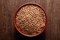 Rustic ceramic bowl of uncooked lentils on dark wood