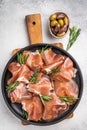 Rustic Charcuterie Board with Jambon Crudo and herbs on a textured stone surface. Royalty Free Stock Photo