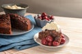 Rustic chocolate cake with morello cherries and whipped cream on a blue napkin and a wooden table, copy space, selected focus Royalty Free Stock Photo