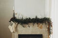 Rustic christmas fireplace with warm knitted stockings and stylish decoration on fir branches. Cozy stockings hanging on mantel in Royalty Free Stock Photo