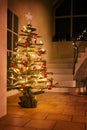 Rustic Christmas tree made of raw wood branches decorated with glowing fairy lights and red balls in a stairwell at night Royalty Free Stock Photo