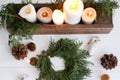 Rustic christmas wreath with candles, pine cones and ornaments on white wooden table, flat lay Royalty Free Stock Photo