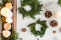 Rustic christmas wreath with candles, pine cones, ornaments on white wooden table, flat lay Royalty Free Stock Photo