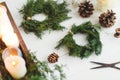 Rustic christmas wreath with candles, pine cones and ornaments on white wooden table Royalty Free Stock Photo