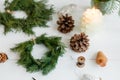 Rustic christmas wreath with candles, pine cones and ornaments on white wooden table Royalty Free Stock Photo