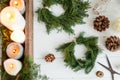 Rustic christmas wreath with candles, pine cones, scissors and ornaments on white  table, flat lay Royalty Free Stock Photo