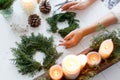 Rustic christmas wreath with candles, pine cones, scissors and ornaments on white wooden table Royalty Free Stock Photo