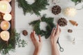 Rustic christmas wreath with candles, pine cones, scissors on white wooden table, flat lay Royalty Free Stock Photo
