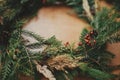 Rustic Christmas wreath detail closeup. Fir branches, pine cones, berries on wooden table. Authentic stylish still life. Making