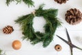 Rustic christmas wreath with pine cones, scissors and ornaments on white wooden table, flat lay Royalty Free Stock Photo