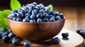 Rustic clay bowl filled with ripe blueberries and fresh spearmint placed on a wooden table