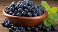 Rustic clay bowl with fresh blueberries and spearmint on wooden table, healthy ingredients