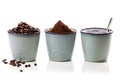 3 rustic coffee cups filled with hot coffee, beans, and ground coffee. White background