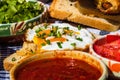 Rustic composition with sausages rolls, fried egg on toast bread, different bowls with sauce and chopped vegetables Royalty Free Stock Photo