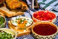 Rustic composition with sausages rolls, fried egg on toast bread, different bowls with sauce and chopped vegetables Royalty Free Stock Photo