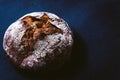 Rustic and crusty round loaf of fresh whole grain bread on dark blue background with white flour on top. top view of buckwheat Royalty Free Stock Photo