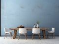 Rustic dining table and white chairs against of blue stucco wall with wooden slab as wall decor. Interior design of dining room Royalty Free Stock Photo