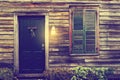 Rustic door and window with closed shutters and porch light