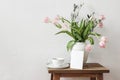 Rustic Easter still life scene. Blank greeting card mockup, cup of coffee and floral bouquet in white ceramic vase on