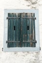 Rustic faded vintage wooden window shutter set in a stone wall