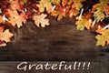 Fall Leaves Lights and Grateful text over Wooden Background Royalty Free Stock Photo
